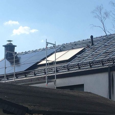 Hausdach mit Sonnenkollektoren und Gerüst unter freiem Himmel.