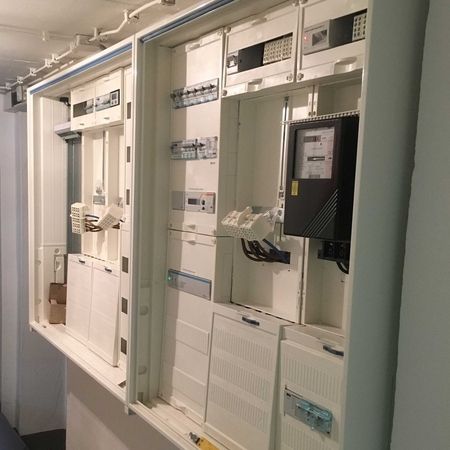 Offene elektrische Schalttafeln und Zähler in einem Hauswirtschaftsraum.