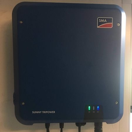 Ein wandmontierter SMA Sunny Tripower Solar-Wechselrichter mit eingeschalteten Kontrollleuchten.