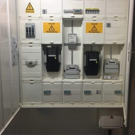 Industrielle elektrische Schaltanlage mit Warnschildern in einem Technikraum.